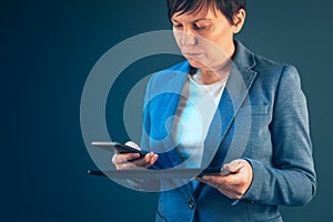 Businesswoman using mobile phone and tablet computer