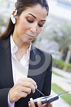 Businesswoman using PDA and earpiece