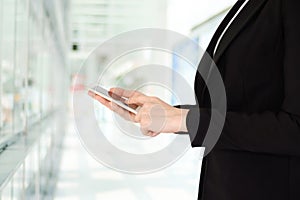 Businesswoman using smart phone over blur office background with copy space for text, people on phone, technology and lifestyle