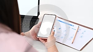 Businesswoman using smart phone for synchronizing data with tablet.