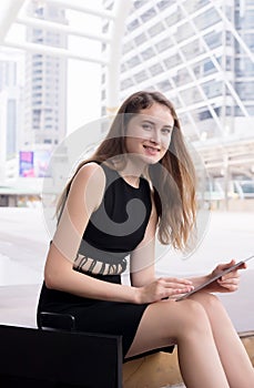 Businesswoman using a tablet computer sitting and working outdoor,Happy with smiling