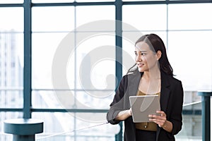 Businesswoman using tablet computer standing near workplace, touching. Young female office worker using apps at her tablet