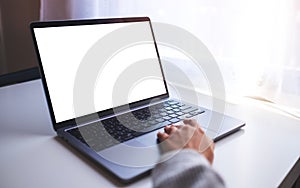 A businesswoman using and touching on laptop computer touchpad with blank white desktop screen on the table