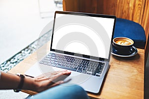 A businesswoman using and touching on laptop touchpad with blank white desktop screen in cafe