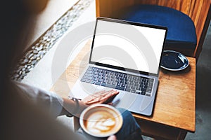 A businesswoman using and touching on laptop touchpad with blank white desktop screen in cafe