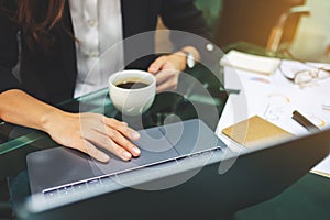 Businesswoman using and touching on laptop touchpad while drinking coffee