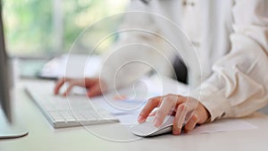 A businesswoman using a wireless mouse, working on her business tasks on computer