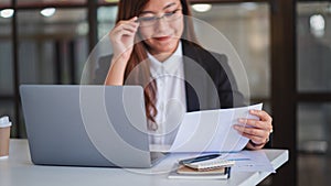 Businesswoman using and working on laptop computer and paperwork in office