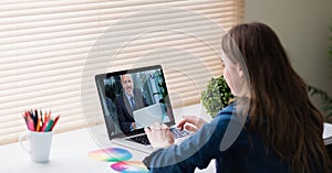 Businesswoman video conferencing with colleague on laptop