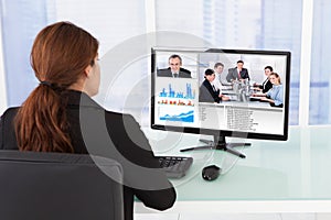 Businesswoman video conferencing with team on computer