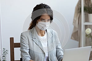 Businesswoman in virus protective facemask working on computer in office. photo