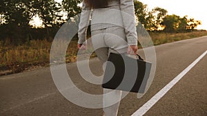 Businesswoman walking down road with a black briefcase in her hand