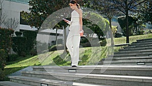 Businesswoman walking down stairs street looking telephone. Rich woman coffee