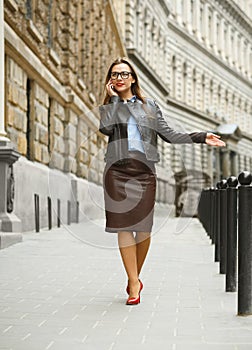 Businesswoman walking down the street while talking on smart phone