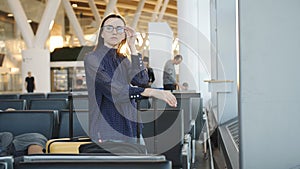 Businesswoman watching of the plane standing at the airport window at sunset in the evening. Travel concept, people in