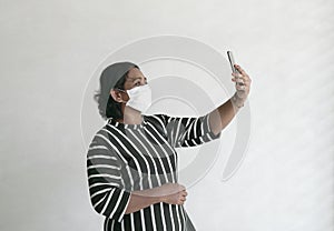 Businesswoman wearing face mask taking a selfie with her cellphone