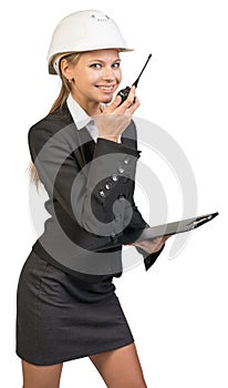 Businesswoman wearing hard hat holding clipboard