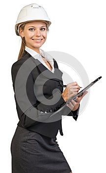 Businesswoman wearing hard hat, writing on