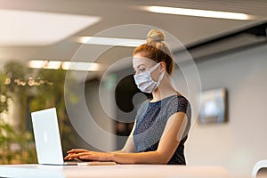 Businesswoman wearing protective face mask working in a modern office