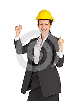 A businesswoman wearing a yellow construction helmet smile while raising her fist up