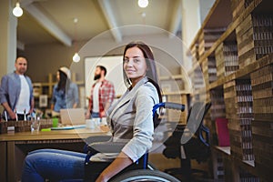 Businesswoman on wheelchair by desk