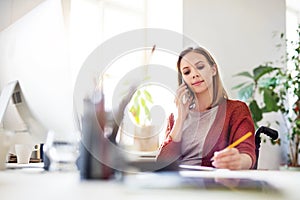 Businesswoman in wheelchair at the desk in her office.