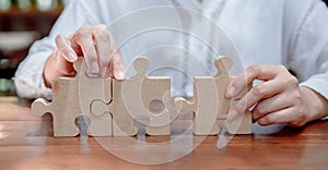 Businesswoman with wooden puzzle and jigsaw for business success concept. Teamwork and achievement