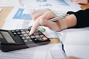 Businesswoman working on calculator to calculate business data the financial report on table