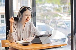 Businesswoman working in coffee shop remotely using and mobile tablet