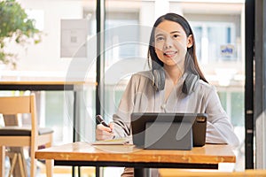 Businesswoman working in coffee shop remotely using and mobile tablet