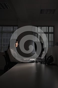 Businesswoman Working On Computer In Dark Office