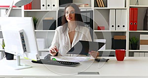 Businesswoman working at computer in light office and looking at kamera.