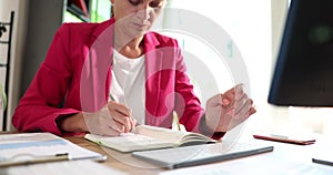 Businesswoman working on computer using typing corporate message and writing notes in notepad