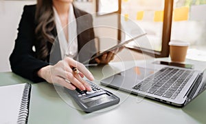 Businesswoman working on desk office with using a calculator to calculate the numbers, finance accounting