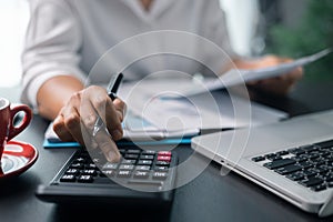 Businesswoman working on desk office with using a calculator to calculate the numbers, finance accounting concept. Woman