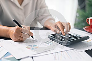 Businesswoman working on desk office with using a calculator to calculate the numbers, finance accounting concept. Woman