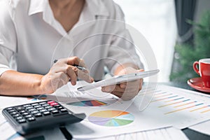 Businesswoman working on desk office with using a calculator to calculate the numbers, finance accounting concept. Woman