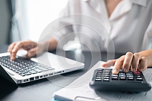 Businesswoman working on desk office with using a calculator to calculate the numbers, finance accounting concept. Woman