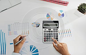 businesswoman working on desk using calculator and laptop analyzing finance accounting in office