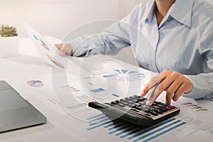 businesswoman working on desk using calculator and laptop analyzing finance accounting in office