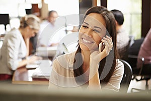 Businesswoman Working At Desk Using Mobile Phone