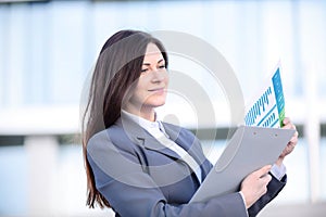 Businesswoman working on digital tablet outdoor over building background