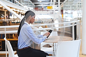 Businesswoman working on digital tablet at table in a modern office