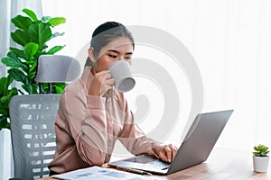 Businesswoman working and drinking coffee at her desk. Enthusiastic