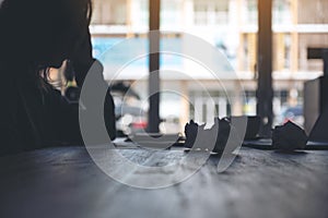 Businesswoman working with feeling frustrated and stressed with screwed up papers and laptop on table in office