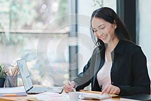 A businesswoman is working at her desk, using a calculator to perform calculations. Finance and accounting concept.