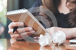 A businesswoman working and holding a white blank notebook with screwed up papers on table