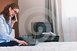 Businesswoman working in hotel room, using laptop and mobile phone