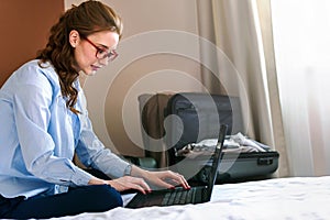 Businesswoman working in hotel room, using laptop and mobile phone