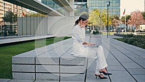 Businesswoman working laptop bench urban street. Woman answering call earbuds